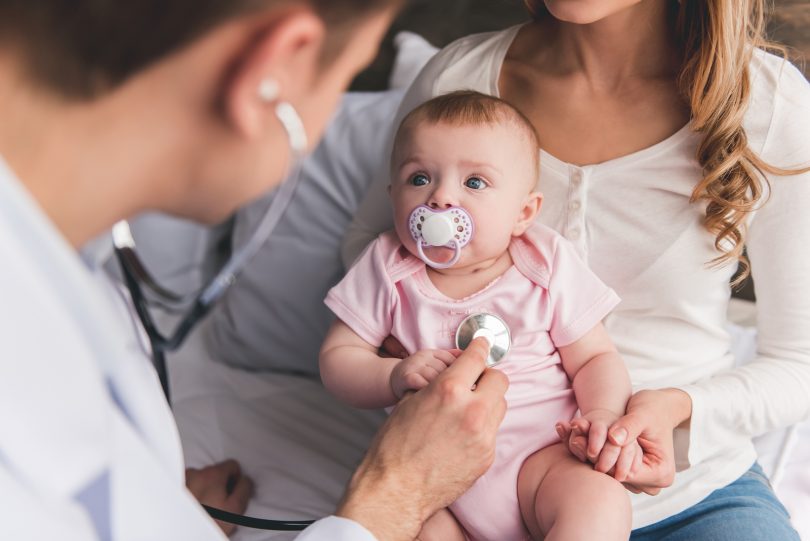 Baby looks at doctor while he's listening to her lungs.
