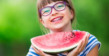 smiling girl with braces eating watermelon