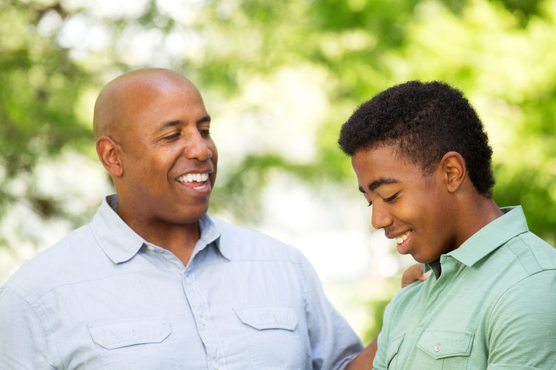 African American father talking to his teen son.
