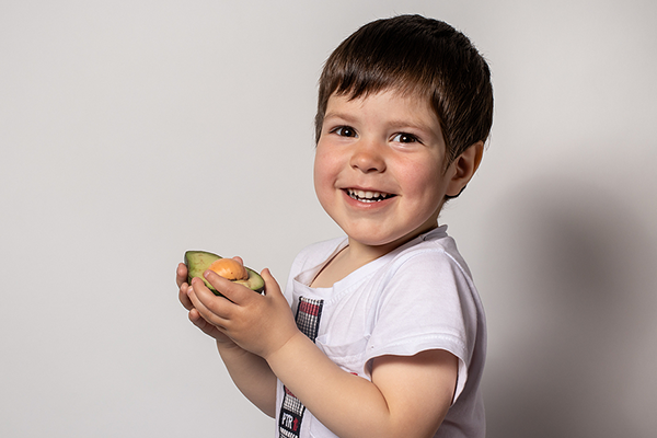 Little boy eating avocado