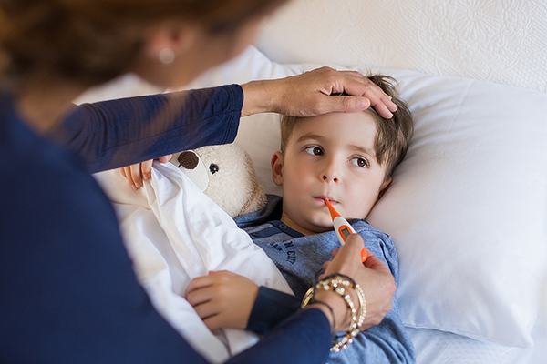 Mom taking son's temperature with thermometer