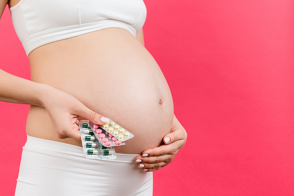 Pregnant woman holding supplements