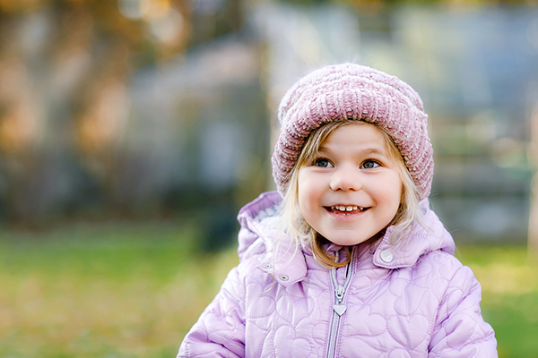 Little girl outside in cold weather wearing a hat and jacket