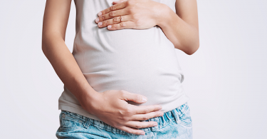 Pregnant teen holding stomach